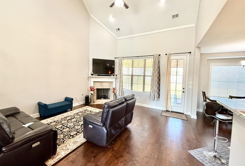 Living area featuring high vaulted ceiling, dark wood-style flooring, a high end fireplace, and ornamental molding