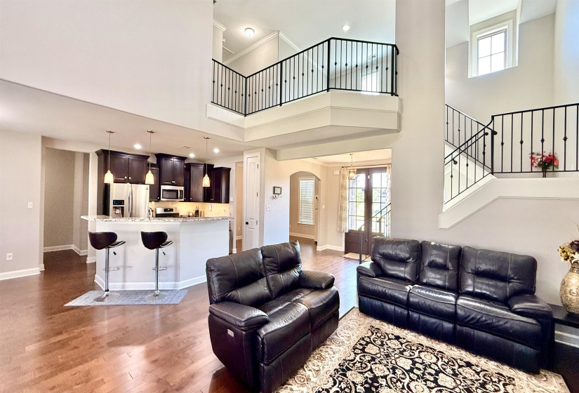 Living room featuring arched walkways, a high ceiling, light wood-style flooring, recessed lighting, and stairs