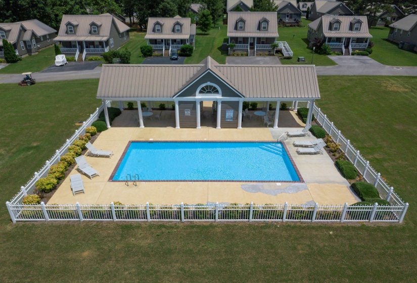 Community swimming pool with a covered pavilion, concrete decking, and white picket fencing