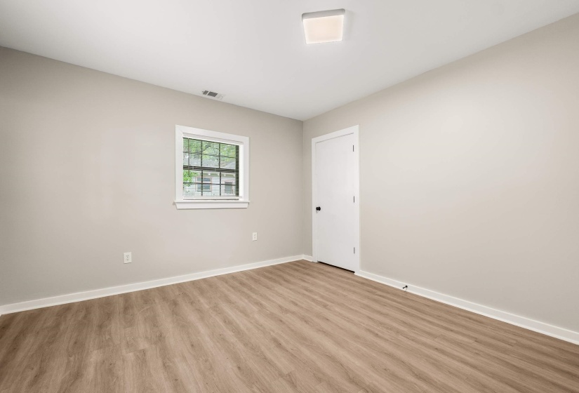 Room featuring wood-finish flooring, neutral wall paint, and white trim