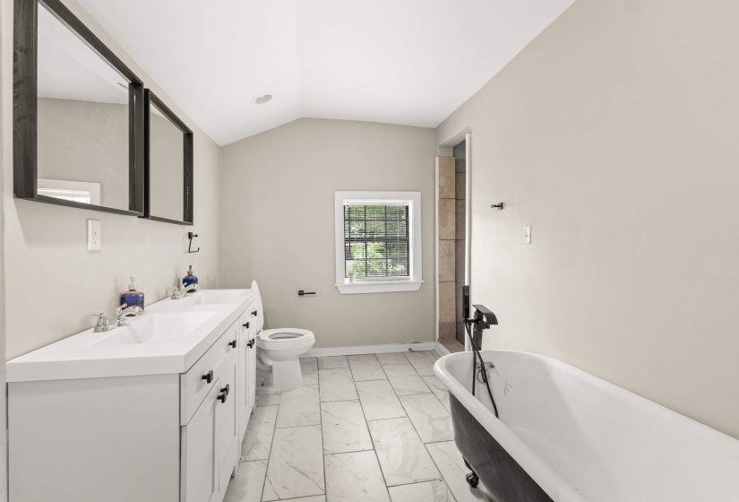 Spacious bathroom featuring a dual vanity, freestanding clawfoot tub with matte black fixtures, and a tiled shower stall