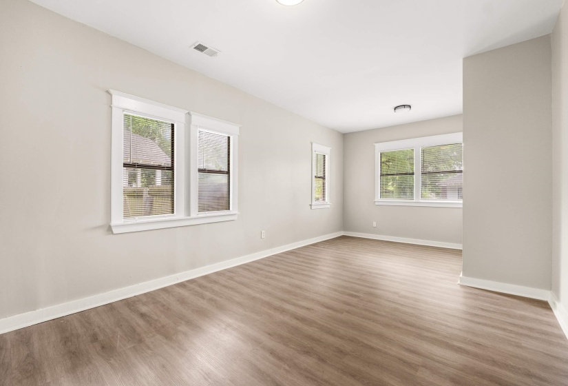 Spacious room featuring wood-finish flooring, light neutral wall tones, and white trim