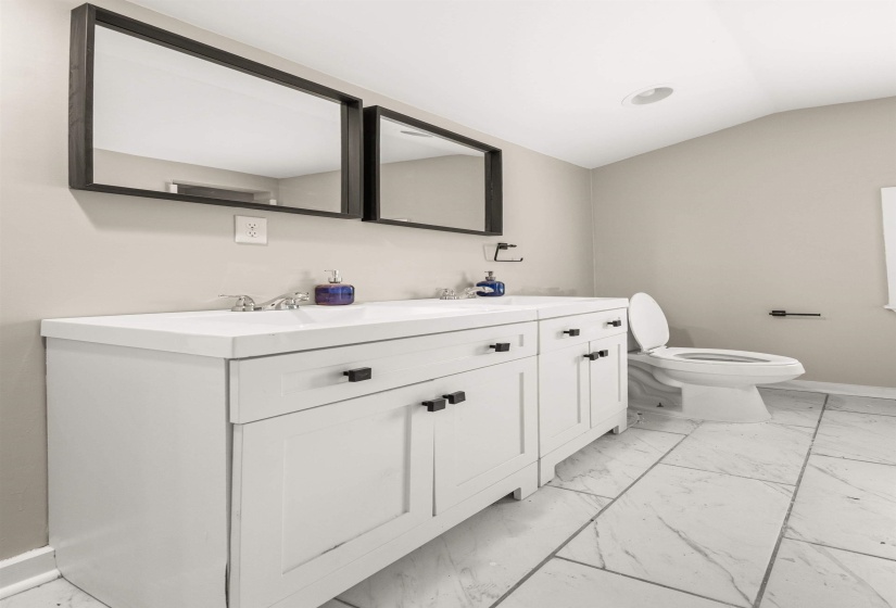 White dual vanity with integrated sinks and black hardware, set against light neutral walls