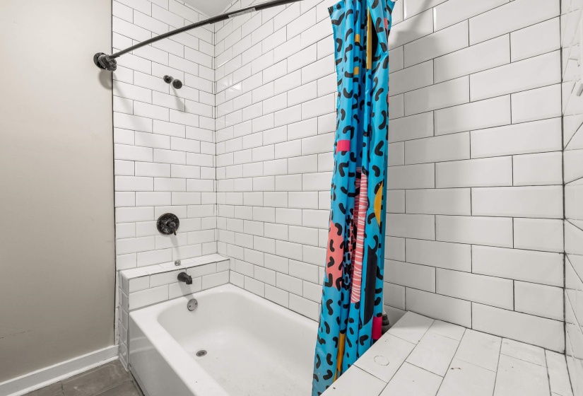 Bathtub with subway tile surround, dark-finish fixtures, and integrated tiled shelving
