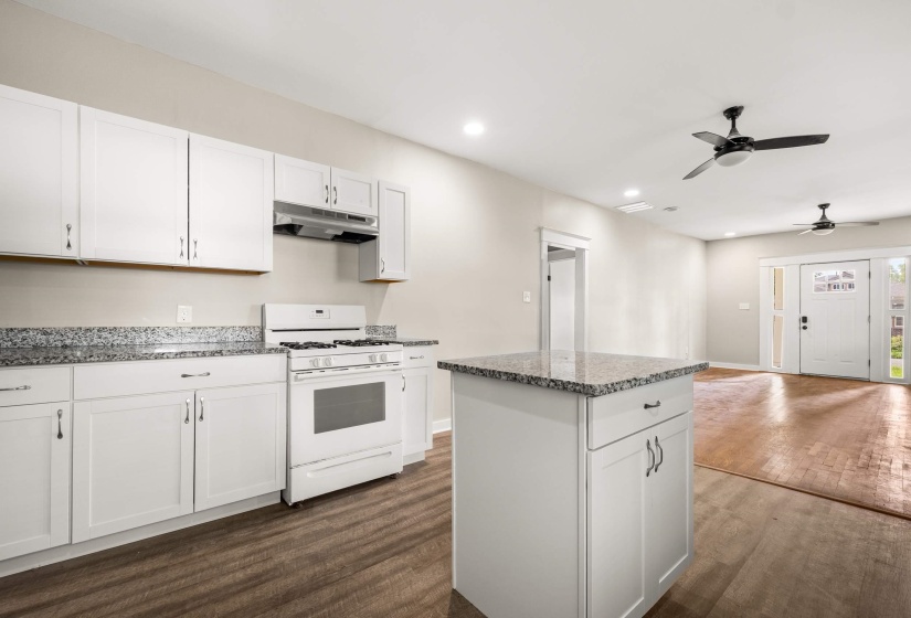 Kitchen featuring white cabinetry, speckled countertops, and a central island
