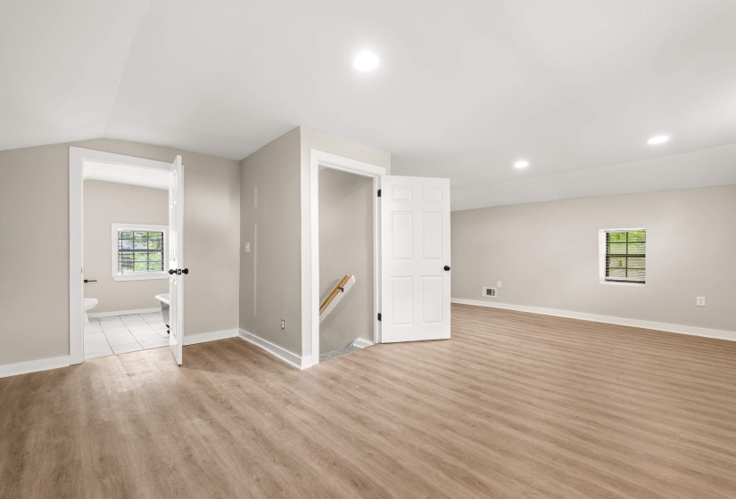 Spacious room with wood-finish flooring, recessed lighting, neutral wall tones, and white trim