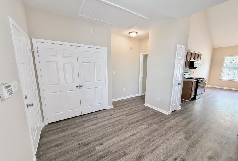 Spacious interior featuring wood-finish flooring, white paneled doors, and vaulted ceilings