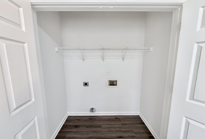 Dedicated laundry space featuring a wire shelving unit, utility hookups, and wood-finish flooring