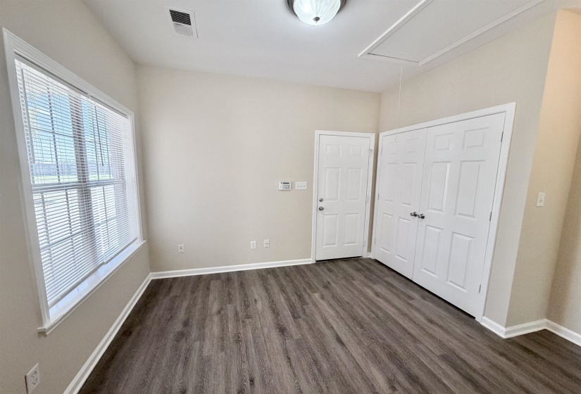 Spacious room featuring wood-finish flooring, light neutral wall tones, and a white ceiling with an overhead light fixture