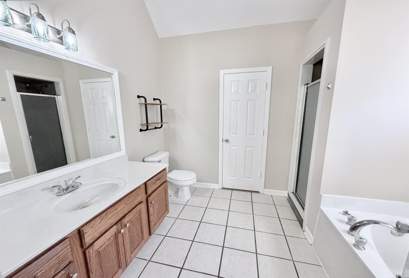 Bathroom featuring a dual-sink vanity with wood cabinetry, a white countertop, and an integrated mirror with overhead lighting