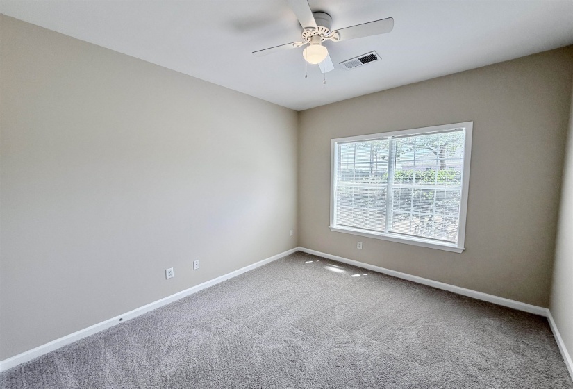Carpeted room with a ceiling fan, a window, and neutral-toned walls