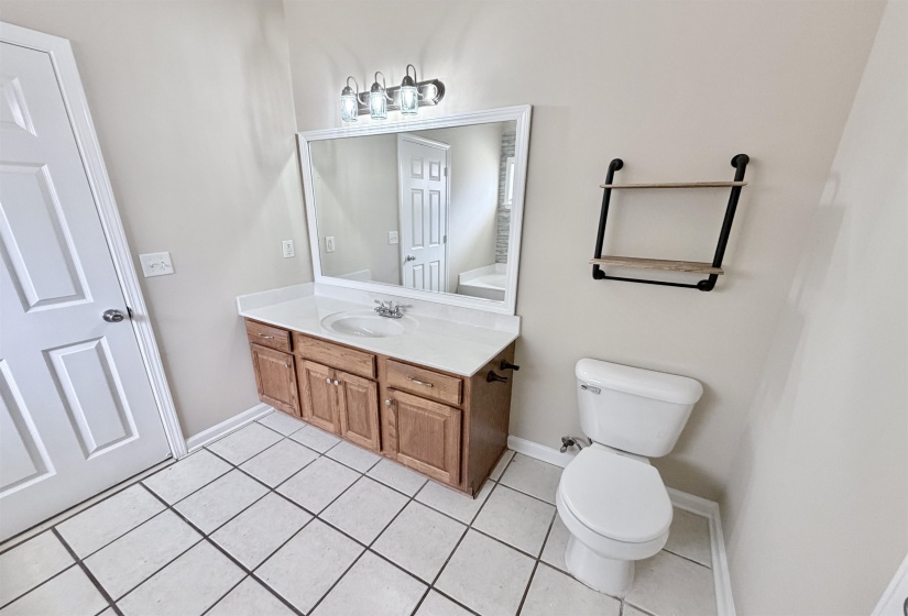 Bathroom featuring a wood-finish vanity with a white countertop and integrated sink, a rectangular mirror, and a three-light fixture