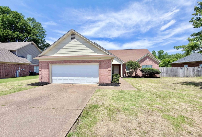 Brick and siding exterior featuring an attached garage, covered entryway, and a fenced backyard