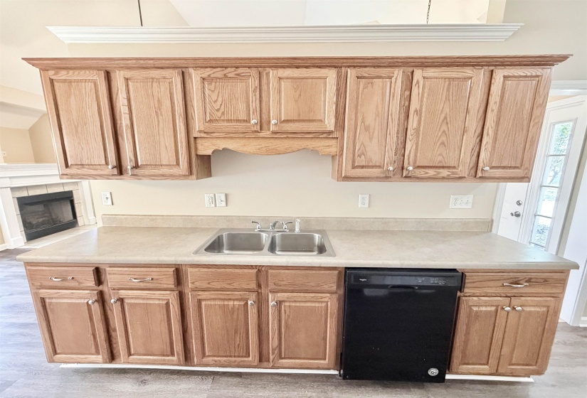 Kitchen featuring light wood-finish cabinetry with silver-tone hardware, a double basin stainless steel sink with a chrome faucet, and a black dishwasher