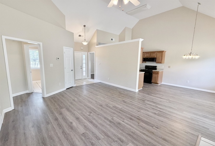 Expansive living area featuring vaulted ceilings, wood-finish flooring, and neutral wall tones