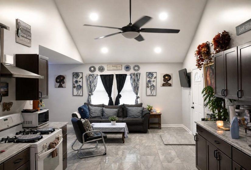 Vaulted ceiling featuring a ceiling fan and recessed lighting, wood-finish flooring, dark wood cabinetry, and light-toned countertops