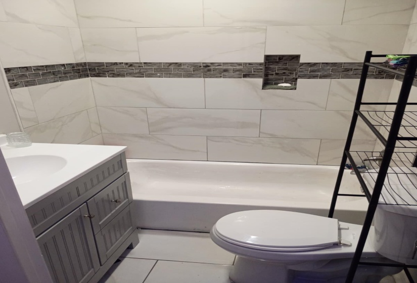 Bathroom featuring a white subway tile surround with a decorative mosaic accent band and a recessed niche