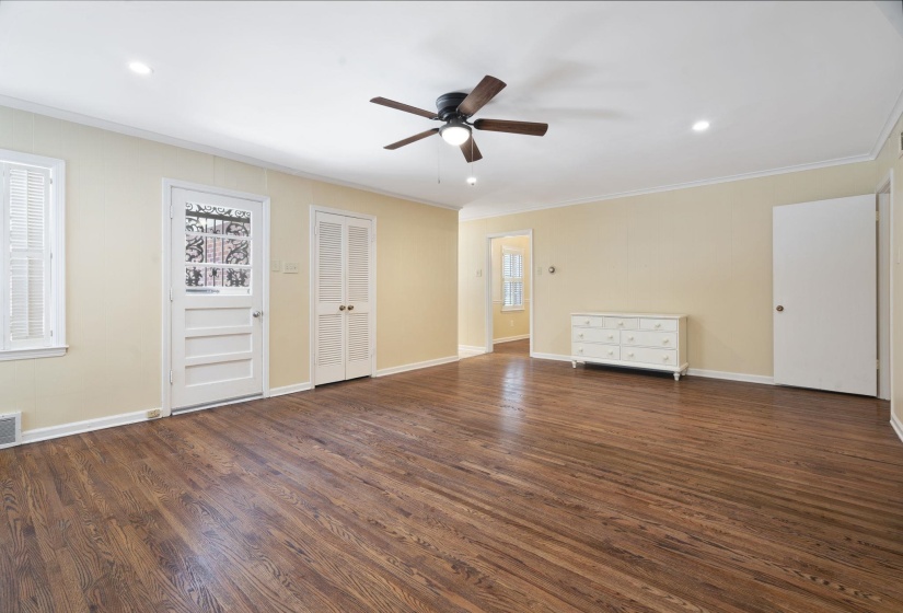 Large living area featuring beautiful hardwood flooring, a white brick fireplace with a mantel, multiple windows with blinds, recessed lighting, and a ceiling fan