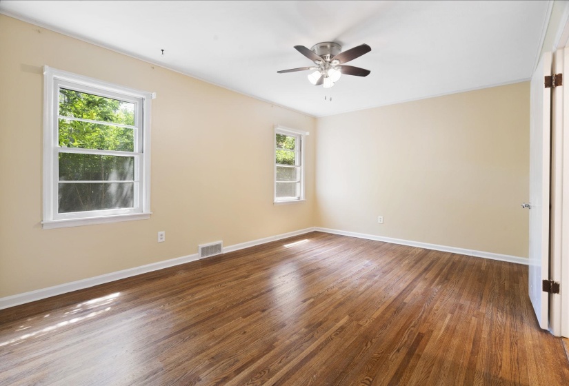 Spacious room featuring wood-finish flooring, light-toned walls, and white trim