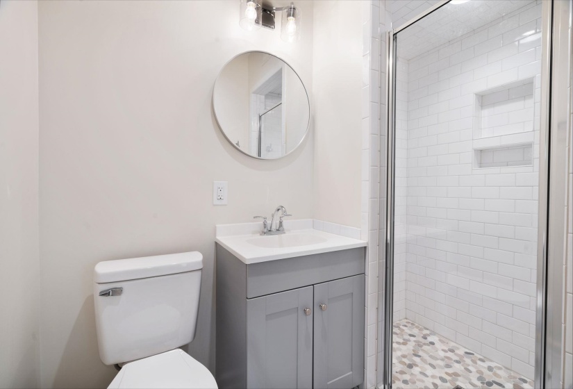 Bathroom featuring a glass-enclosed shower with subway tile walls and a pebble-finish floor