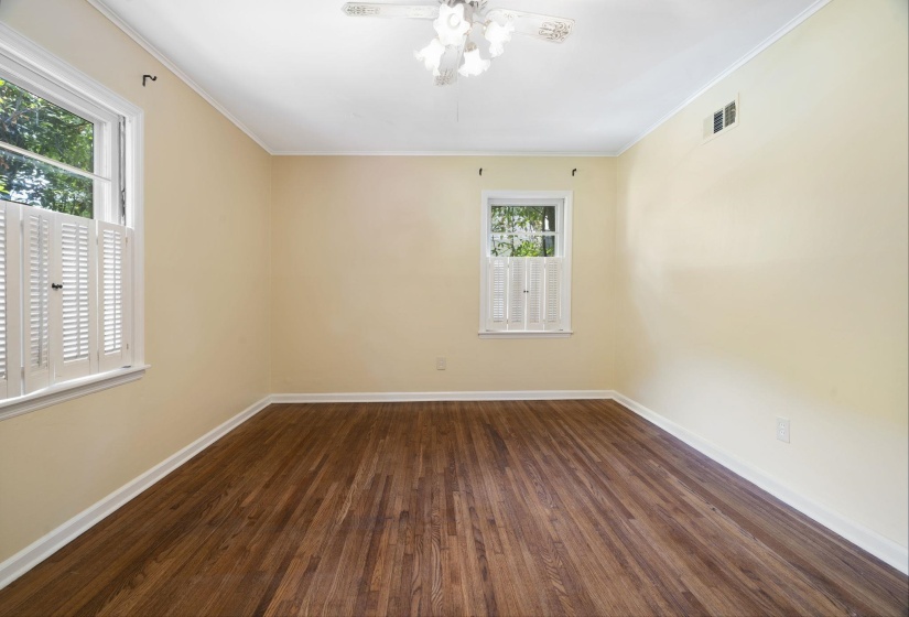 Room featuring rich wood-finish flooring, light-toned walls, and white crown molding