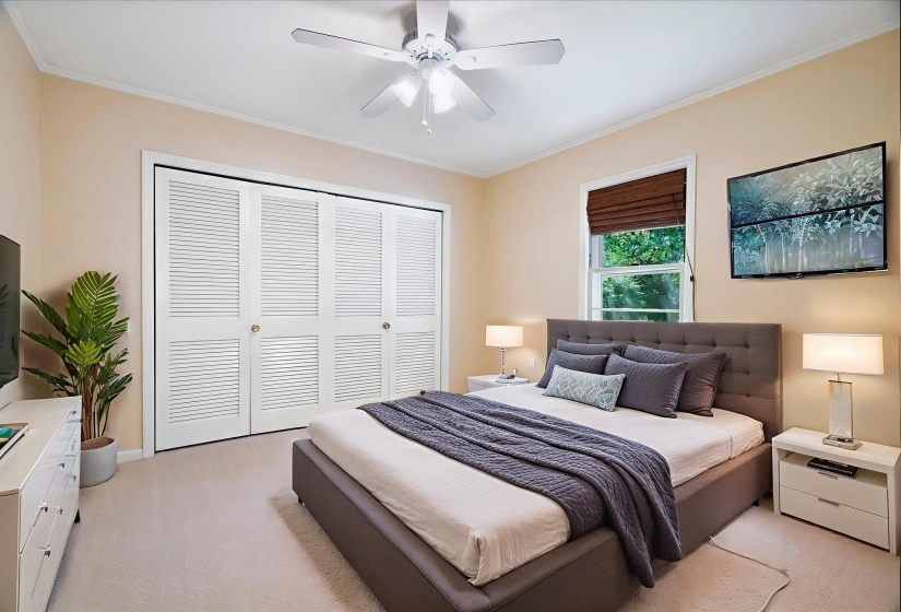 Bedroom featuring neutral wall colors, soft carpeting, a window with a brown roman shade, and louvered bifold closet doors