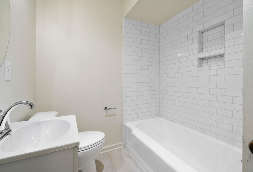 Renovated Bathroom featuring a white subway tile tub surround with an integrated niche and beautiful tile flooring
