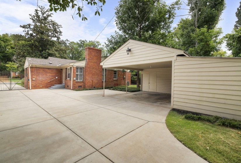 Expansive concrete driveway servicing a brick exterior residence with a covered carport