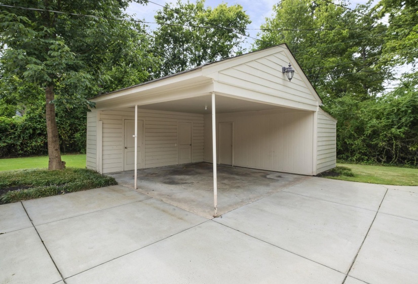Carport with concrete flooring, three storage areas, and an overhead light fixture.