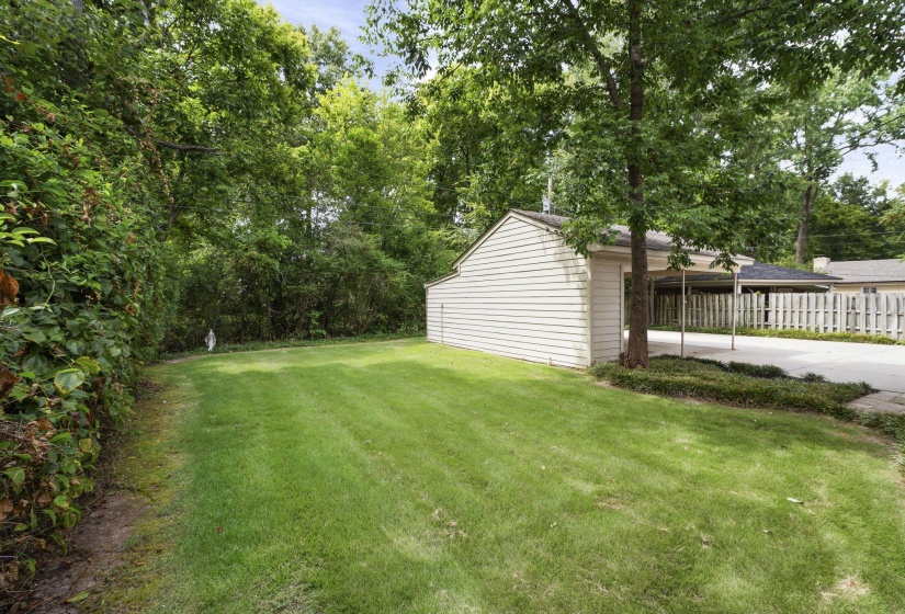 Expansive grass lawn bordered by mature trees and established greenery
