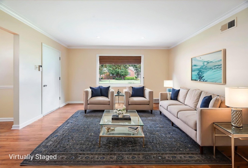 Spacious interior room featuring beautiful hardwood flooring, light neutral wall paint, and white crown molding