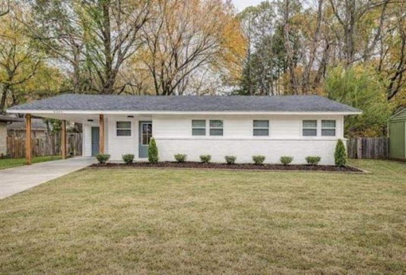 Single-story residence featuring a carport with wood posts, white brick and siding exterior, a dark gray shingle roof, and a concrete driveway