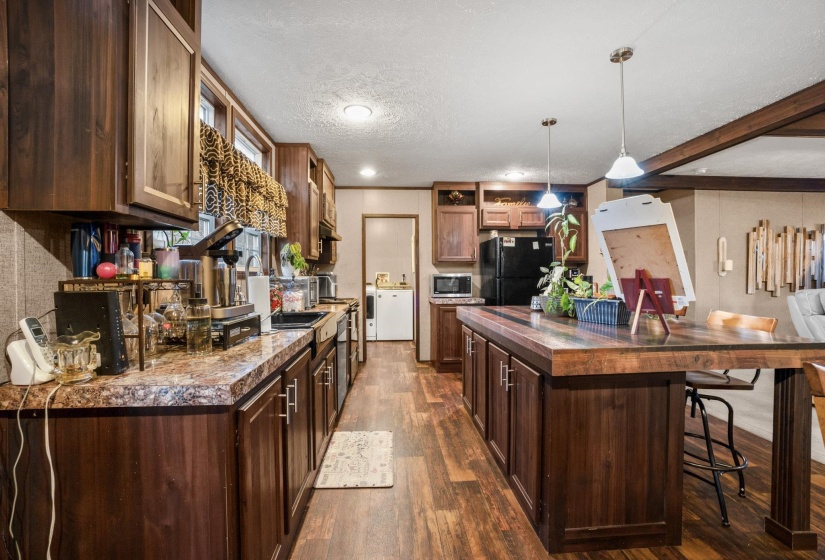Kitchen featuring wood-finish flooring, dark wood cabinetry, a patterned countertop, and a substantial kitchen island with seating