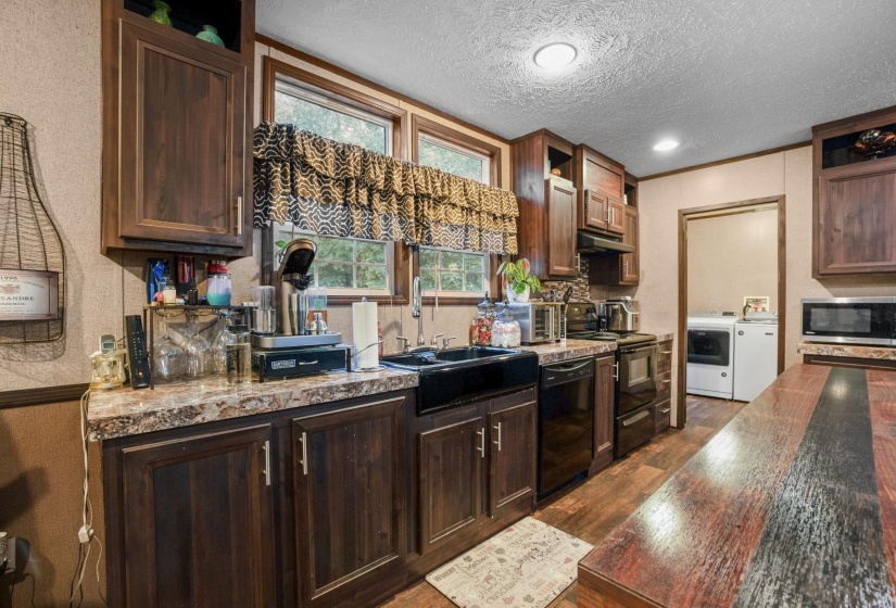 Kitchen featuring dark wood cabinetry, a black farmhouse-style sink, and patterned countertops
