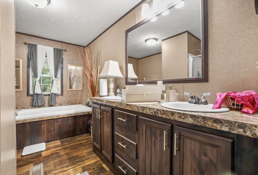Bathroom vanity featuring dual inset sinks, a framed mirror, and wood-finish cabinetry
