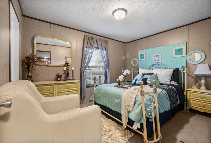 Bedroom featuring a window with blinds, soft carpet flooring, a wall-mounted light fixture, and horizontal wall paneling