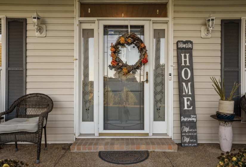 Inviting front entrance with a white storm door featuring decorative glass panels and a transom window