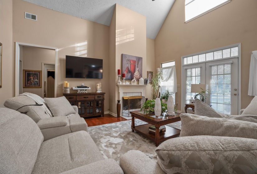 Living area featuring vaulted ceilings, a fireplace with a white mantel, and wood-finish flooring
