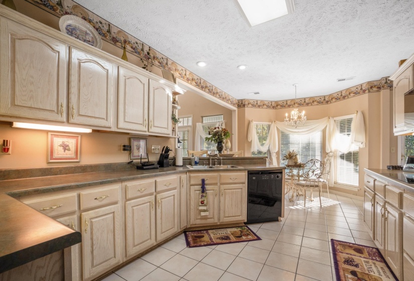 Kitchen featuring light-toned cabinetry, a black dishwasher, and white tile flooring