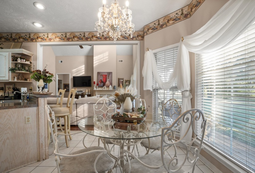 Dining area featuring a crystal chandelier, large windows with blinds, and tile flooring
