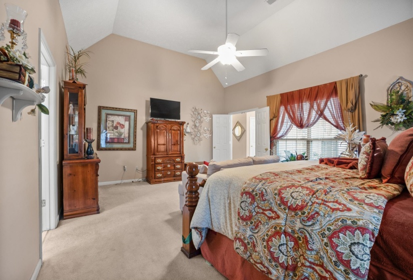 Carpeted room featuring a vaulted ceiling and a ceiling fan with integrated lighting