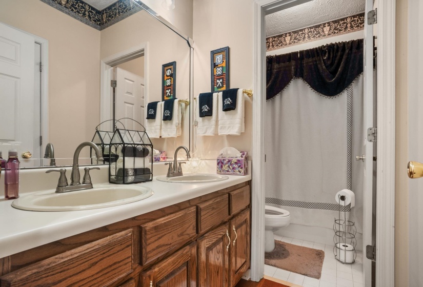 Dual basin vanity with wood-finish cabinetry, brushed nickel faucets, and a full-width mirror