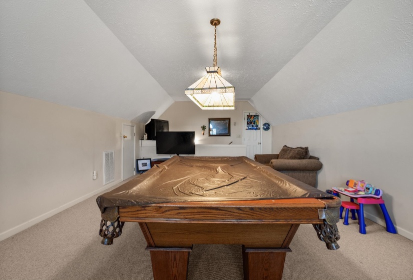 Spacious bonus room featuring a sloped ceiling, recessed wall, and neutral carpet flooring