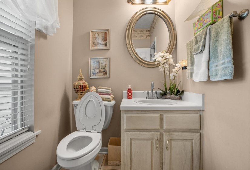 Bathroom featuring a single vanity with a white countertop and light-toned cabinetry, an oval mirror, and a window with blinds