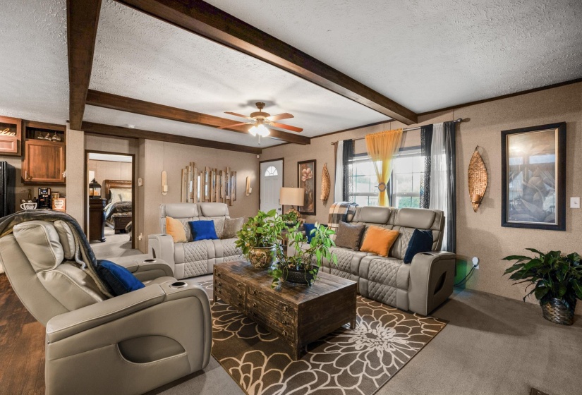 Living area featuring exposed ceiling beams and a ceiling fan