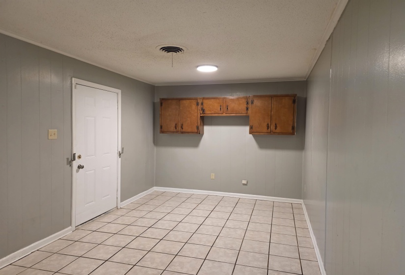 Laundry area with wooden walls, a textured ceiling, crown molding, and light tile patterned flooring