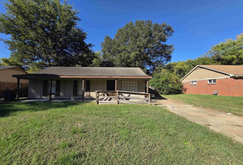 View of front of home with a front yard, a porch, and concrete driveway