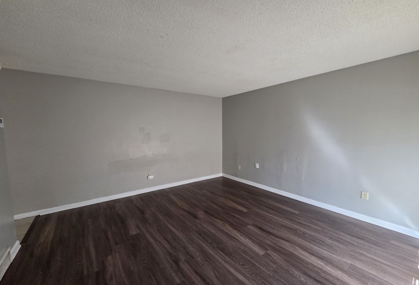 Empty room with dark wood-style floors and a textured ceiling