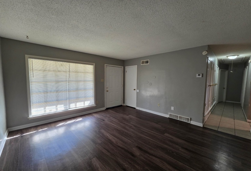 Unfurnished living room featuring attic access, a textured ceiling, and wood finished floors