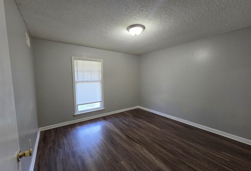 Empty room with dark wood-style flooring and a textured ceiling